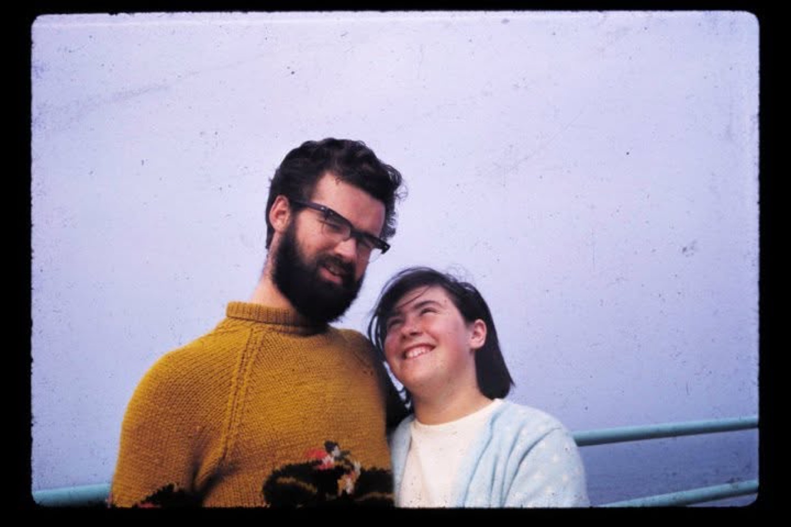 Sam and Susan as a young couple, from one of Sam's film slides. Susan smiles up at Sam, who wears glasses, a full beard, and a mustard-yellow sweater.