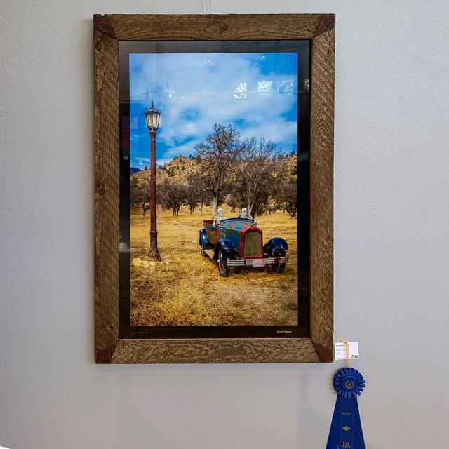 Ghost Riders framed in barn wood on a gallery wall, a blue First Place ribbon hanging beside it.